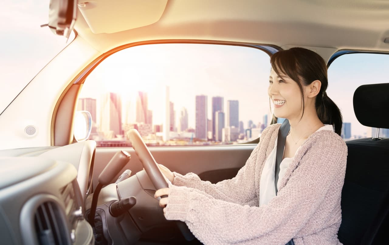 日の光が窓から当たっている車の室内。女性が運転中。