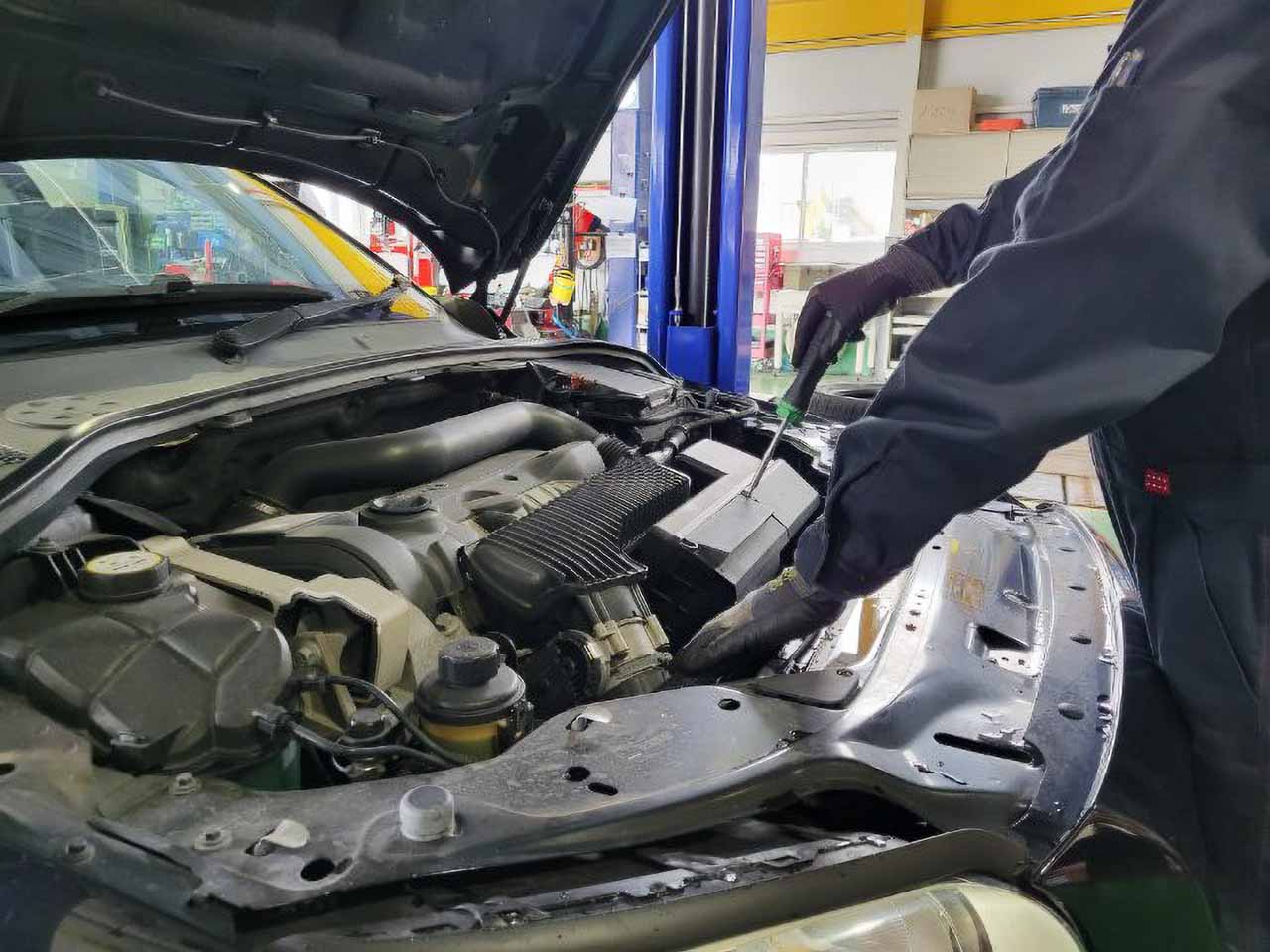 ボンネットを開けて、車検 エアーエレメント交換作業をしている整備士