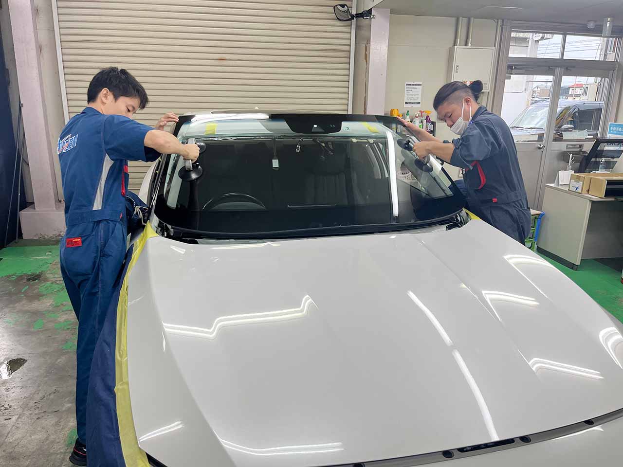 2人がかりで慎重にフロントガラスを車体に取り付ける