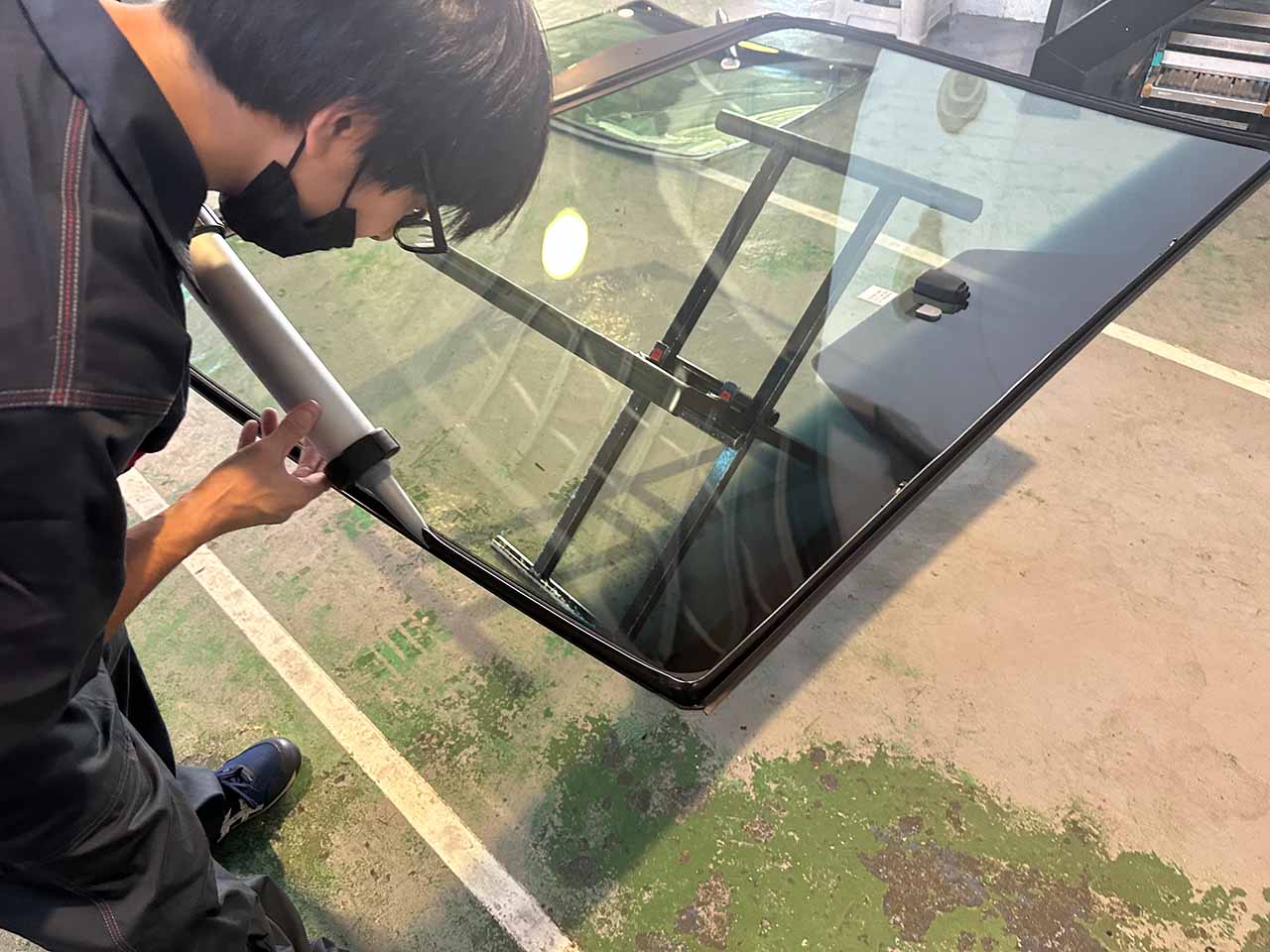 ベテランのスタッフによるフロントガラスの接着剤の充填作業