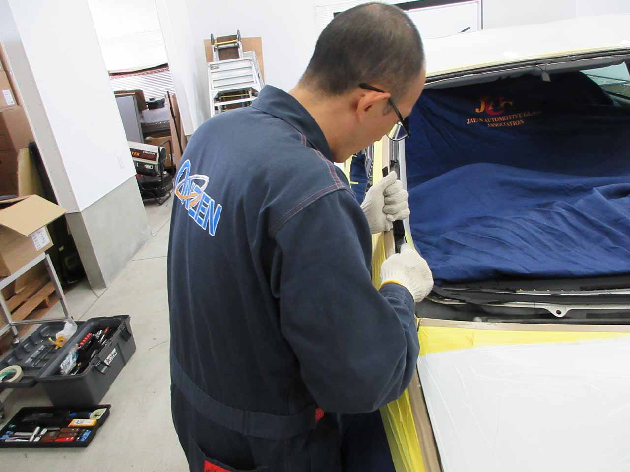 フロントガラスについた古い接着剤の除去作業